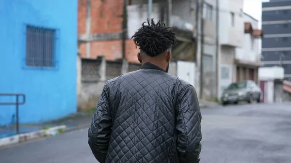A pensive person walking outside in street one Brazilian man walks forward