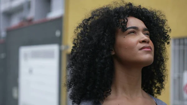 A latina black woman looking at sky with eyes closed feeling hopeful