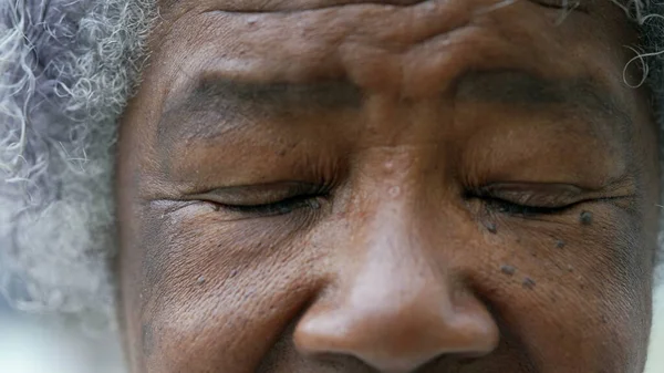 A black older woman closing eyes in meditation macro eyes closeup