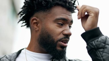 Kıvırcık saçlarıyla oynayan Afrikalı bir adam