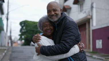 An adult son embracing elderly mother family love affection outside