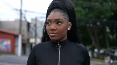 Genç siyahi bir kadın şehir sokağında kameraya doğru yürüyor.