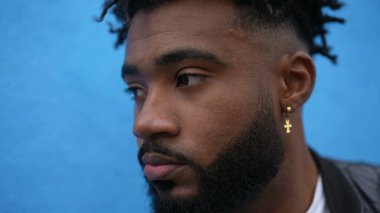 Sokakta duvara yaslanan düşünceli bir Afrikalı adam