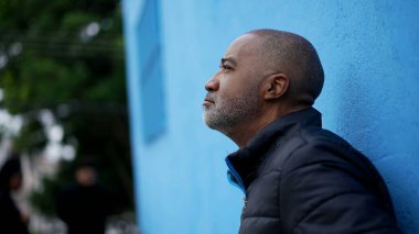 Düşünceli bir siyahi kıdemli adam sokakta dikilip karar vermeyi düşünüyor.