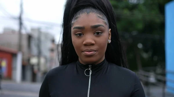 A young black woman walking forward toward camera outside in urban street