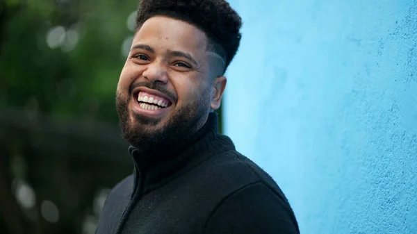 A young black man laughing and smiling portrait face a hispanic latin Brazilian person turning head to camera