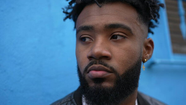 Задумчивый африканский мужчина, прислонившийся к стене на улице и думавший: