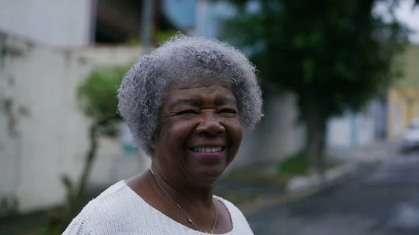 A Brazilian latin older woman in 70s with gray hair outside in urban street tracking shot