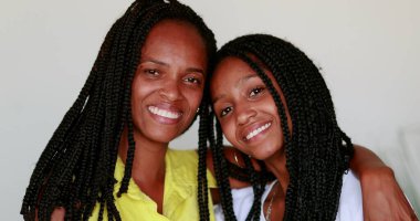 Anne ve kızı birlikte poz veriyorlar. Afrikalı siyah ırk kameraya gülümsüyor