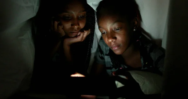 Две Сестры Одеялом Ночью Смотрят Видео Смартфоне — стоковое фото