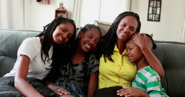 Mixed race mother and kids sitting at couch