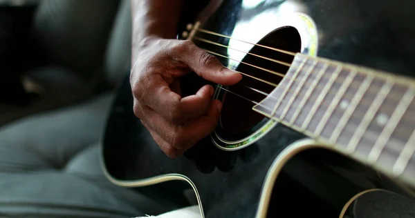 Black man hands playing guitar. African person practicing with musical instrument closeup hand