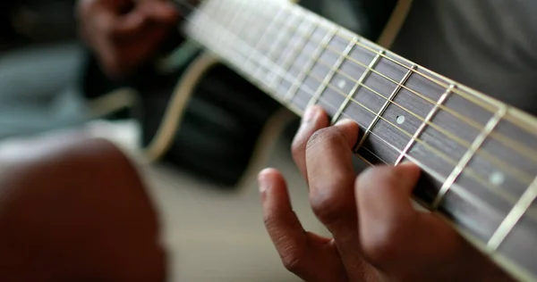 Black man hands playing guitar. African person practicing with musical instrument closeup hand