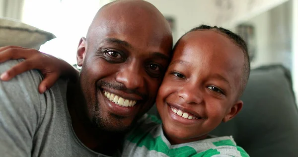 Black father and boy posing to camera. African child bonding