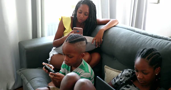 African family using technology devices at home, black parents and children looking smartphones and laptop