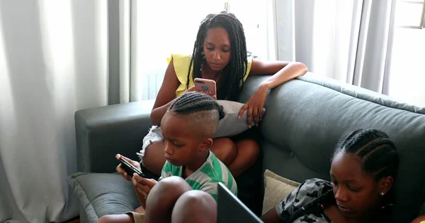 African family using technology devices at home, black parents and children looking smartphones and laptop