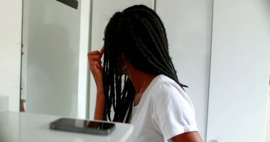 Black teen girl checking herself in front of mirror. African american teenager