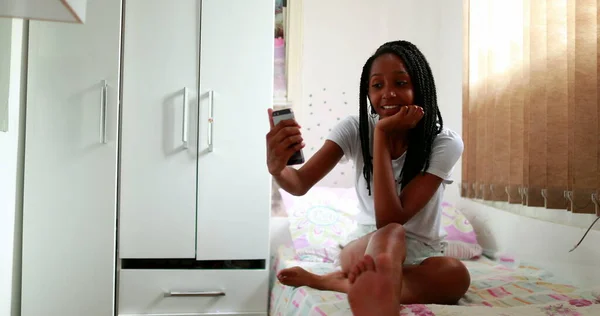 Teen girl speaking on video phone with friend. African mixed race adolescent in long-distance communication