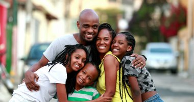 Happy African family portrait standing for photo outside. Cheerful black parents and children