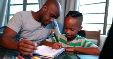 Baba, oğluna ev ödevinde yardım ediyor. Afrikalı siyahi baba küçük çocuğa akıl hocalığı yapıyor