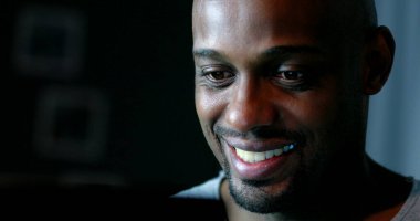 Geceleri bilgisayar ekranına bakan siyah bir adam yüzü.