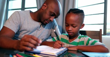 Afrikalı Amerikalı baba, küçük oğluna ders veriyor.