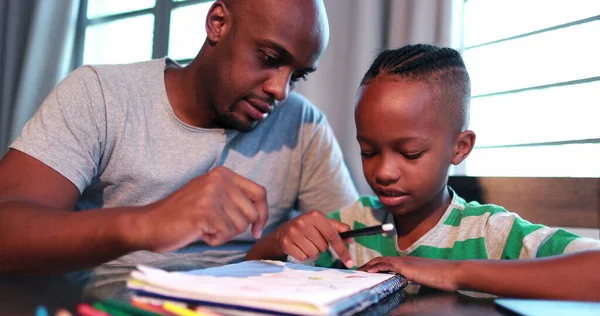 Little boy studying at home doing homework with father help