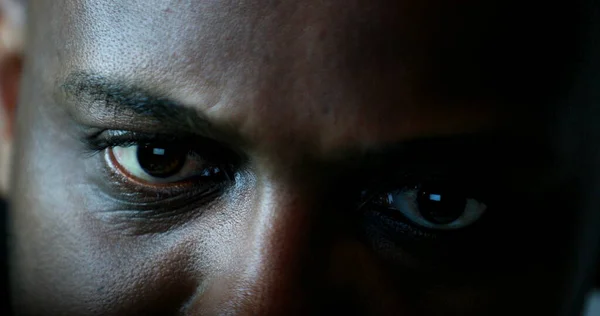 Close-up black man face and eyes looking at laptop computer screen at night