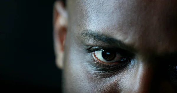 Close-up black man face and eyes looking at laptop computer screen at night