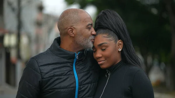 A black father kissing a teen daughter on forehead family love and affection