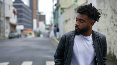 Şehir sokaklarında yürüyen genç bir adam öne doğru yürür.