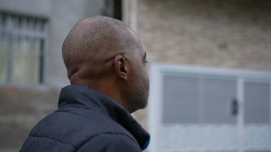 Dürbünlü bir Afrikalı adam sokakta dalgın bir siyahi olarak yürüyor.