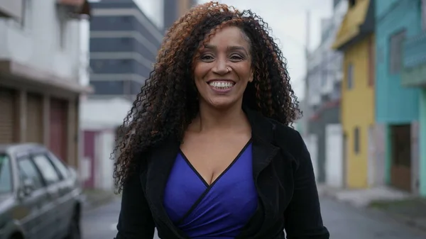 A latin black woman walking forward in urban street smiling