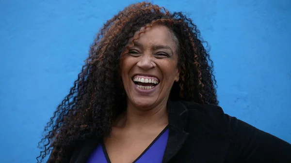 A happy diverse latin person in 40s laughing and smiling on blue background