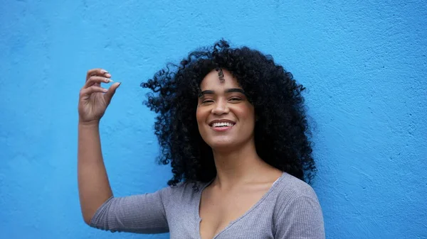 A black diverse woman standing outside in blue background laughing and smiling