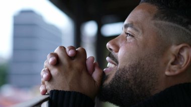 Genç adam Tanrı 'ya dua ederken umutla ve inançla gökyüzüne bakıyor.