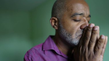 Endişeli yaşlı siyahi bir adam Tanrı 'dan yardım diliyor. Endişeli bir son sınıf öğrencisi elleriyle yüzünü ovuşturuyor umutsuz hissediyor.