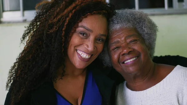 Afrikalı yaşlı bir anne ve yetişkin bir kız birlikte poz veriyorlar.