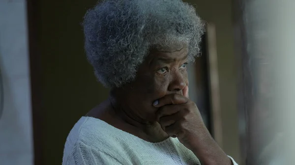 Düşünceli bir Afrikalı son sınıf öğrencisi. Pencerenin önünde dikiliyor. Düşünceli bir siyahi 80 'li yaşlarda.