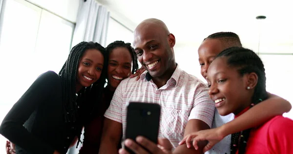 Black family gathering together to speak through cellphone camera with family