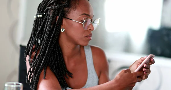 Black African woman checking smartphone device, reading content online