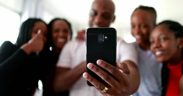 Black African family speaking with family member through smartphone camera