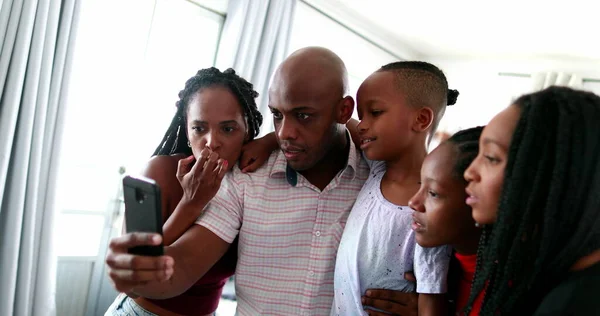 Black African family gathered together staring at cellphone