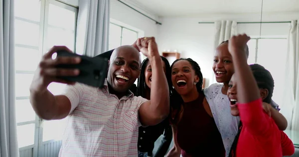 African family cheering success together looking at cellphone