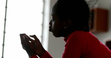 Zenci genç kız tırnaklarına bakıyor.