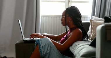 Evde çalışan Afrikalı bir kadın bilgisayarda yazı yazıyor.