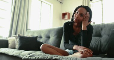 upset black teen girl at home sofa looking at cellphone device feeling frustration