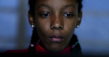 Ergen, geceleri bilgisayar ekranına bakıyor internette geziniyor, siyah Afrikalı etnik kökenli genç kız okuyor.