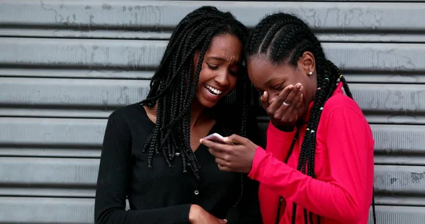 Две Черные Подружки Смеются Используя Смартфон — стоковое фото