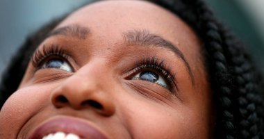 Calm woman closing and opening eyes in meditation. Contemplative African person smiling feeling free